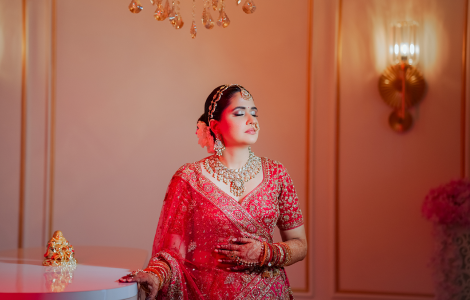 A beautiful bride wearing a vibrant red lehenga and intricate jewellery, elegantly portrayed in bridal photography.