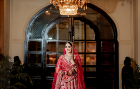 A beautiful bride adorned in a red lehenga, showcasing grace and charm in a captivating bridal photography moment.