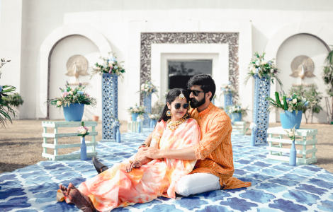 Destination photography of a couple dressed in Indian attire, sitting gracefully on a vibrant blue carpet.