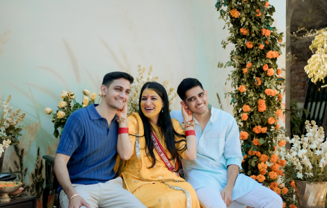 Three people adorned in traditional Indian garments sit on a bench, showcasing the artistry of Haldi Photography.