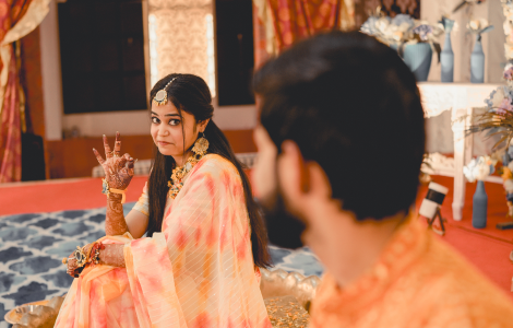 The bride and groom sit on the floor, immersed in a traditional Indian wedding, beautifully framed in Haldi Photography.