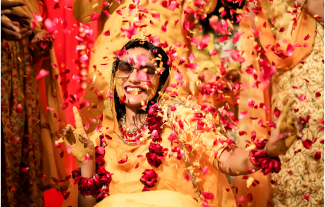 A bride amidst a shower of confetti and flowers, beautifully illustrating the festive spirit of Haldi Photography.