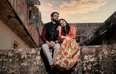  A couple sits on a wall, enjoying each other's company in front of a charming building.