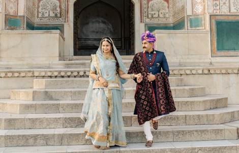 A couple in traditional Indian attire gracefully descends steps during a pre-wedding photography session.
