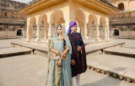 A couple in traditional Indian clothing stands in front of an ancient structure - pre-wedding photography.