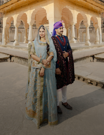 A couple in traditional Indian clothing stands in front of an ancient structure - pre-wedding photography.