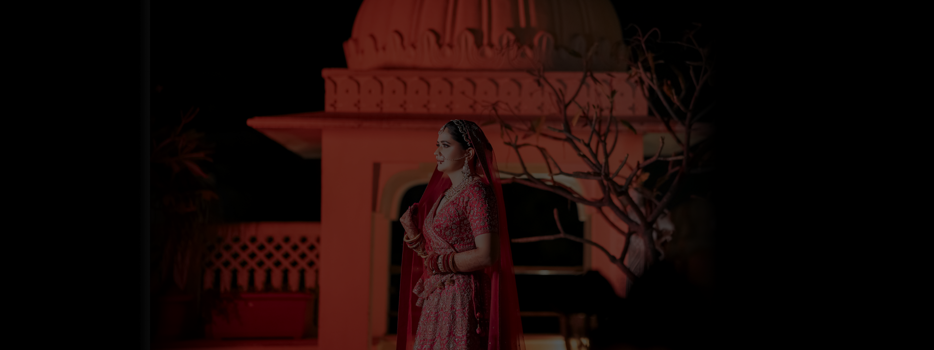 A woman wearing a red lehngaposes in front of a building.