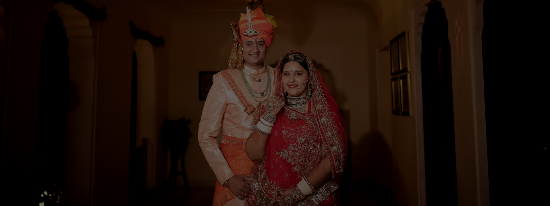 A couple dressed in traditional Indian clothing, featuring rich fabrics and detailed patterns, posing elegantly.
