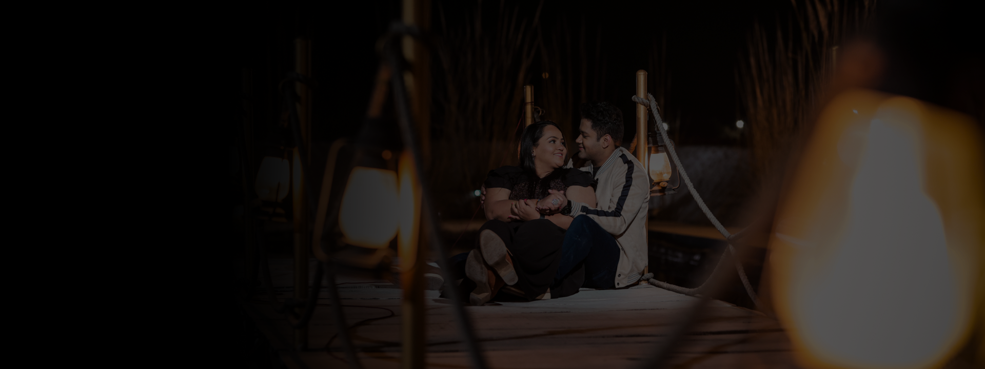 A couple enjoys a serene night on a dock, gazing at the stars and reflecting on their time together.