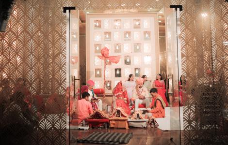 A group of individuals in red attire seated on the floor, captured during a wedding celebration.