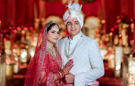 A couple dressed in traditional red wedding attire, showcasing love and joy during their Indian wedding celebration.